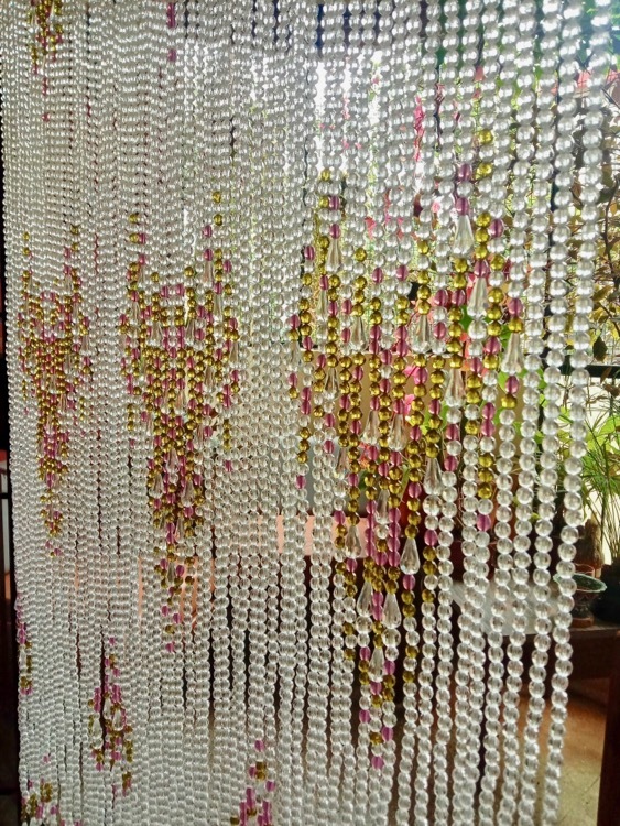 Bead Curtain Shimmering In Sunlight In Balcony Doorway